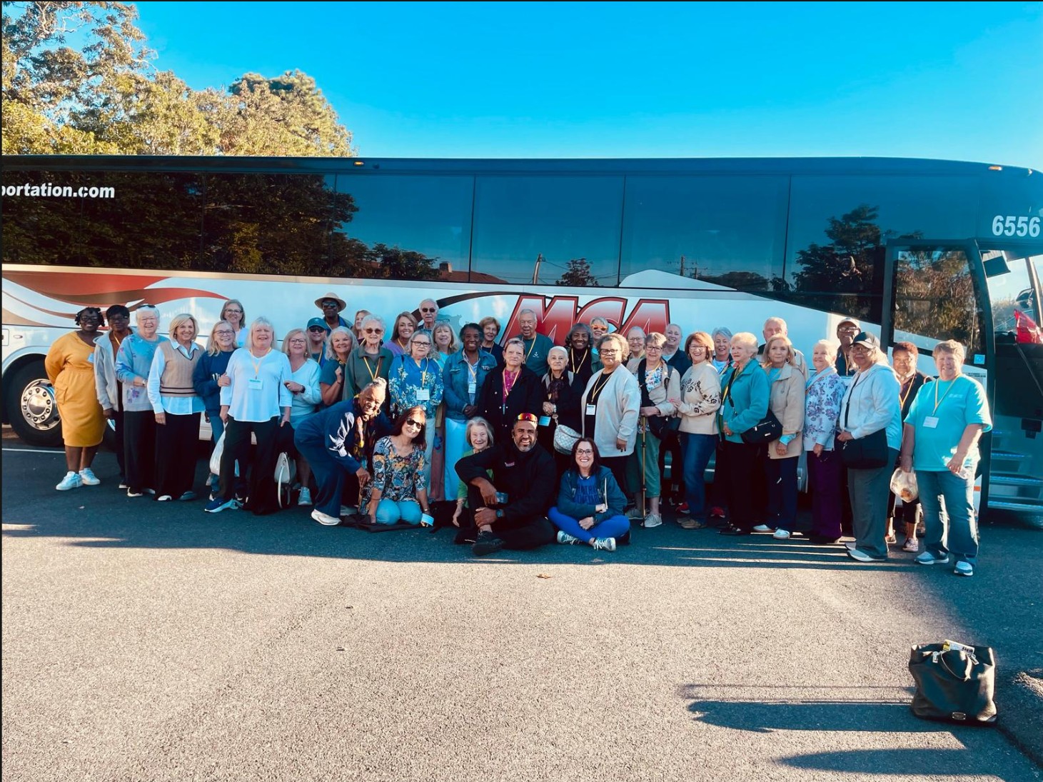 Senior travel group posing in front of an MCA Transportation motorcoach