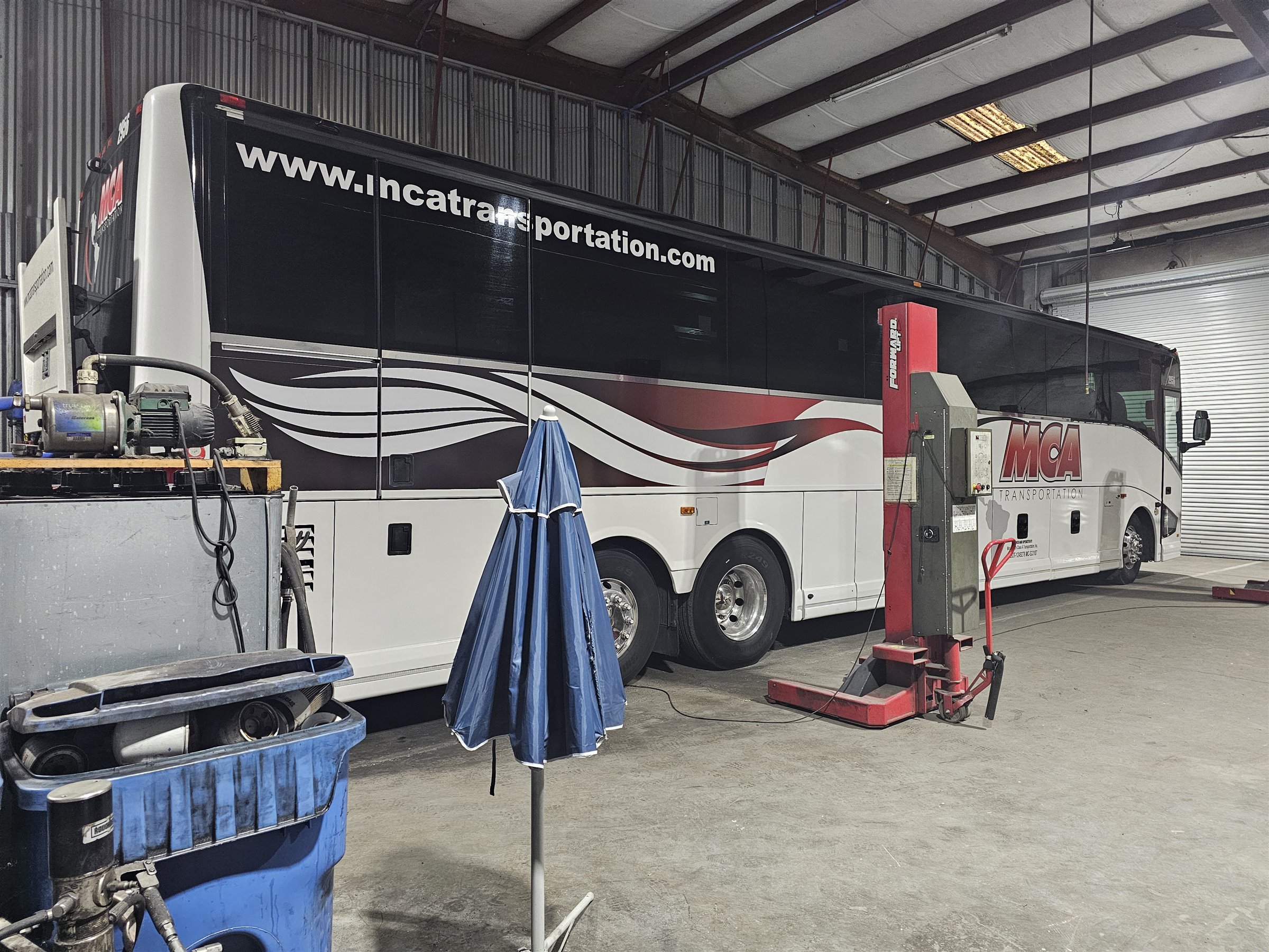MCA Transportation motorcoach beside the shop lift
